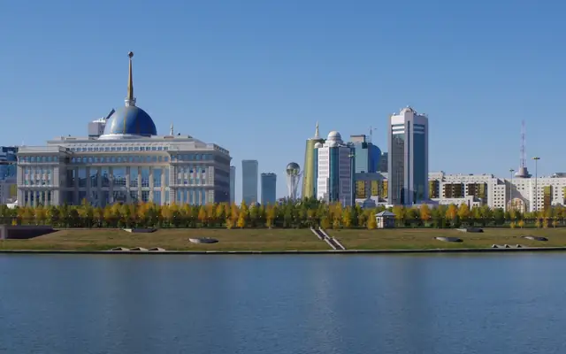 哈萨克斯坦阿斯塔纳市中心伊希姆河畔全景，可见阿克奥尔达总统府、中央音乐厅和城市天际线
